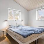 Schlafzimmer mit Bett, zwei Fenstern und Holzboden.