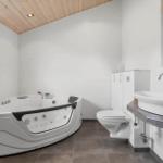 Bad mit Whirlpool, Waschbecken und Toilette unter Holzdecke.