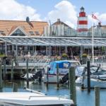 Hafen mit Booten, Restaurant und Leuchtturm im Hintergrund.