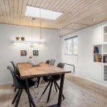 Esszimmer mit Holztisch, schwarzen Stühlen und weißen Schränken an der Wand.