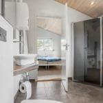 Badezimmer mit Dusche und Blick in Schlafzimmer mit Bett und Fenster.