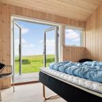 Schlafzimmer mit Bett, Stuhl und Blick auf Grünfläche.