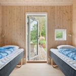 Zwei Betten mit blauen Decken, Holzwände und Tür zum Garten.