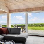 Wohnzimmer mit Sofa, Terrasse und Meerblick durch große Fenster.