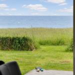 Von der Terrasse aus bietet sich ein Blick auf das Meer und grünes Gras.