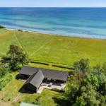Haus mit Terrasse, umgeben von Grünflächen und Strand.