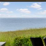 Durch das Fenster ist das Meer und eine grüne Wiese zu sehen.