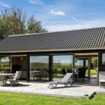 Moderne Villa mit Terrasse, Sitzgelegenheiten und großem Glasbereich. Grün umgeben.