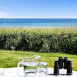 Tisch mit Wasser und Fernglas vor grünem Rasen und Meer.