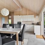 Essbereich mit Tisch und Stühlen, Küche und Terrasse mit Blick auf Grünflächen.