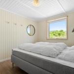 Schlafzimmer mit Bett, Fenster und Wandspiegel.