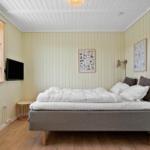 Schlafzimmer mit Bett, Wandbildern und Fenster. Holzboden und weiße Decke.