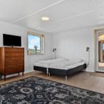 Schlafzimmer mit Doppelbett, Fernseher und Terrassenzugang.