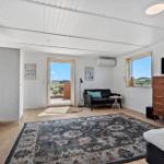 Schlafzimmer mit Bett, TV-Schrank und Sitzgelegenheit. Durchgang zur Terrasse mit Blick.