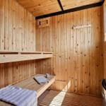 Holzsauna mit Bänken, Handtuch und Steinofen.
