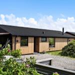 Moderne Holzhütte mit schwarzem Dach und Garten. Einbauküche und Schlafzimmer.