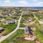 Aerial view of vacation homes on grassy dunes near the sea.