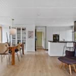 Moderne Küche mit Essbereich und Sitzgelegenheit. Holzboden und weiß gestrichene Wände.