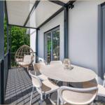 Terrasse mit Esstisch, Stühlen und Hängesessel. Blick in den Wald.