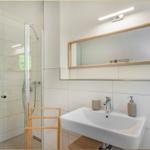 Badezimmer mit Dusche, Waschbecken und Spiegel.