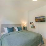 Schlafzimmer mit Bett, Nachttischen und Fernseher an der Wand.