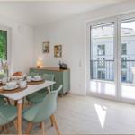 Esszimmer mit Tisch, Stühlen und Balkonansicht.