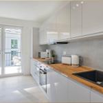 Moderne Küche mit Holz-Arbeitsplatte und Balkonansicht.