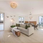 Wohnbereich mit Sofa, Couchtisch und TV. Terrasse über Glastür. Helle Holzböden.