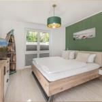 Schlafzimmer mit Bett, Fernseher und Fenster zur Außenseite.