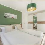 Schlafzimmer mit Bett, grüner Wand und großer Lampe.