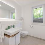 Badezimmer mit Waschbecken, Spiegel und Fenster zur Außenseite.