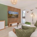 Wohnzimmer mit Sofa, Fernseher und Holzelementen an der Wand.