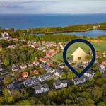 Luftbild einer Wohngegend mit See und Meer im Hintergrund.