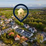 Luftbild von Wohnhäusern mit Wald und See im Hintergrund.