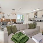 Wohnzimmer mit Sofa, Küchenbereich und Balkonansicht.