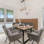 Esszimmer mit Tisch, Stühlen und Blick auf Balkon.