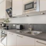 Moderne Küche mit Edelstahlspüle, Dunstabzugshaube und integriertem Mikrowellenherd.