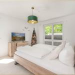 Schlafzimmer mit Bett, Fernseher und Fenster zur Terrasse.