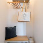 Hängende Tasche und Kleiderhaken über einem Holztisch mit Kissen.