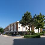 Ferienhaus mit Terrasse und Bäumen an sonnigem Tag.