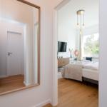 Schlafzimmer mit Bett, Fernseher und Fenster. Spiegel an der Wand.