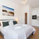 Schlafzimmer mit Bett, Nachttisch und Küchenbereich.