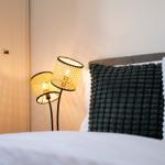 Bettkopf mit Kissen, Stehlampe und Schrank im Schlafzimmer