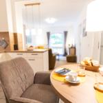 Esstisch mit Stuhl, Kaffeetasse und Brotkorb. Küche und Wohnbereich im Hintergrund.