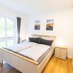 Schlafzimmer mit Doppelbett, Fenster und Nachttischen.