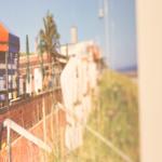 Fensterblick auf Terrasse mit Sonnenschutz und Palmen im Hintergrund.