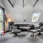 Wohnzimmer mit schwarzen Ledermöbeln, Kamin und großen Fenstern.