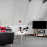 Wohnzimmer mit Sofa, Fernseher und Tisch unter schrägem Dach