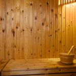 Holzsauna mit Sitzbank und Eimer mit Kelle.