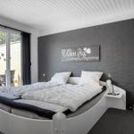 Schlafzimmer mit Bett, Glasfront und Wanddekoration.